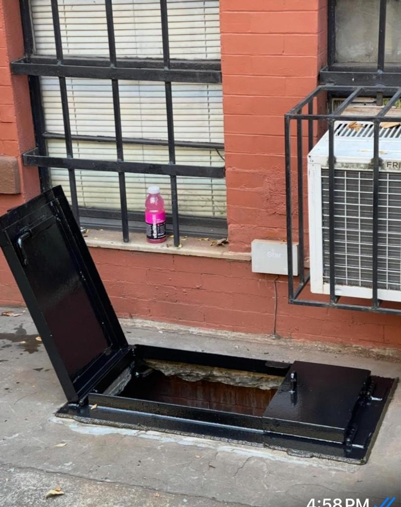 Open basement hatch on urban street