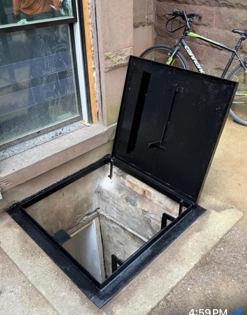 Open basement hatch with bicycle nearby