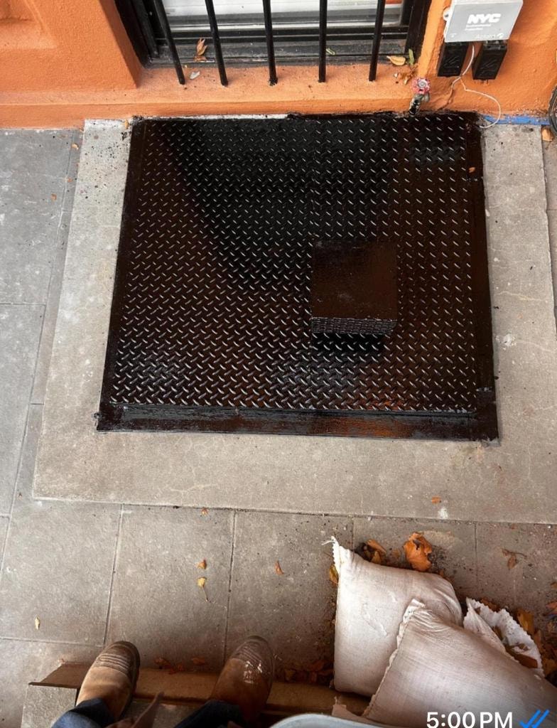 Black diamond-plate sidewalk door on orange building