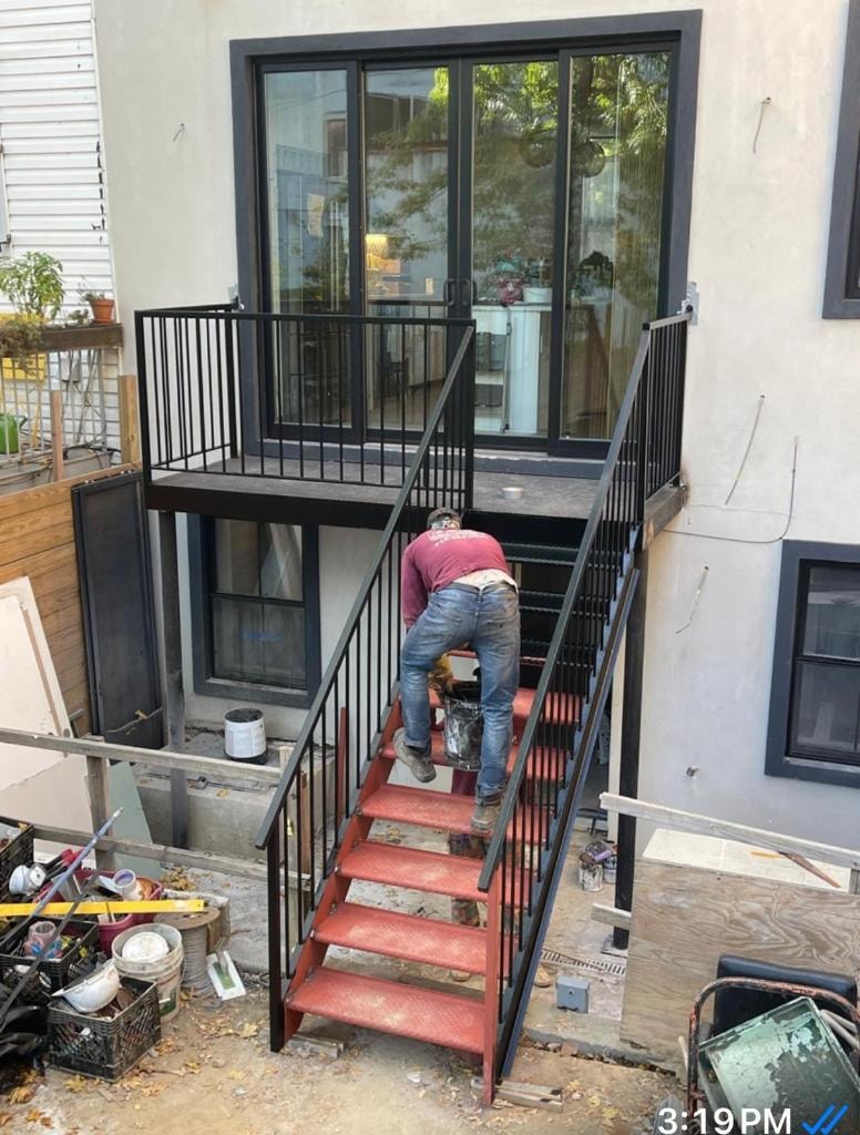 Worker climbing exterior metal staircase construction