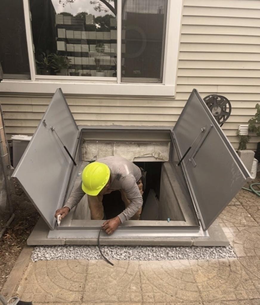 Worker inspecting basement egress window opening
