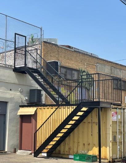 Black metal staircase on industrial building with shipping containers