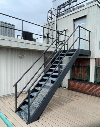 Gray metal rooftop staircase with grated treads and railings