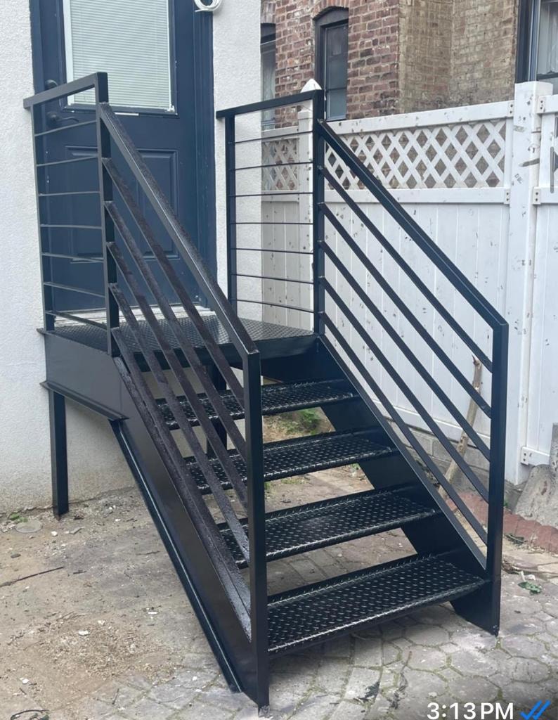 Black metal exterior staircase with diamond-plate treads and cable railings