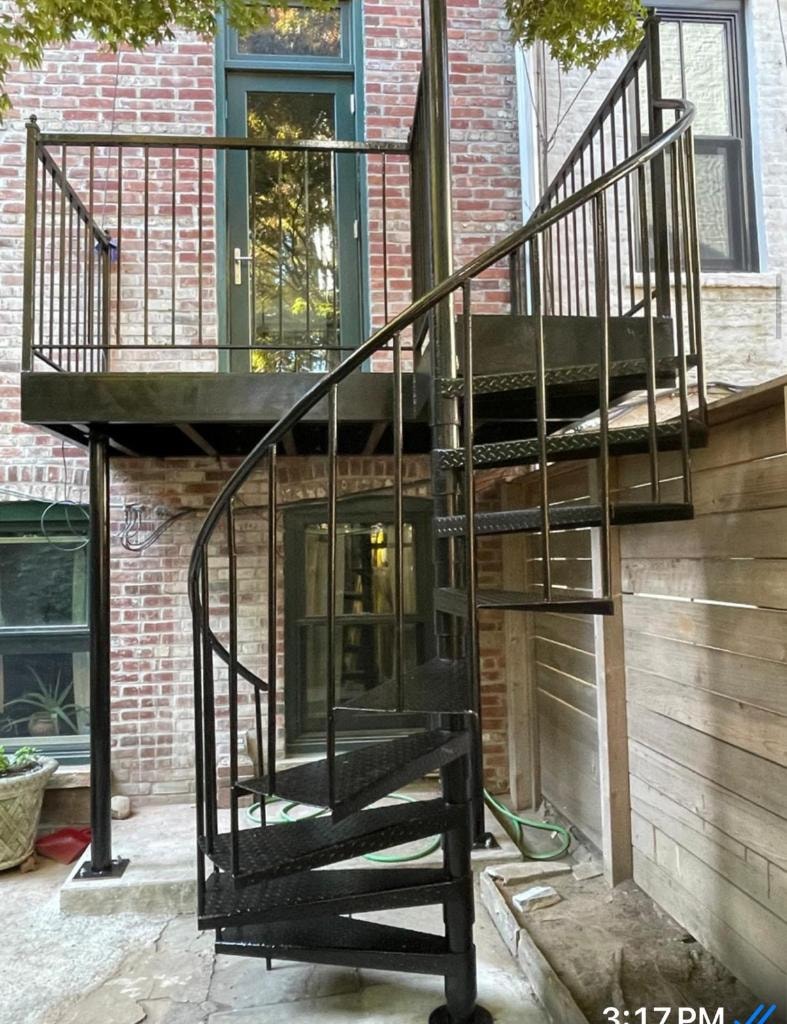 Black spiral staircase with platform and railings on brick building