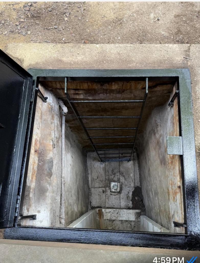 Open basement hatch showing concrete interior and drain