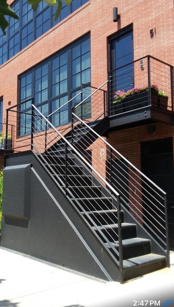 Modern exterior staircase with cable railings on red brick building