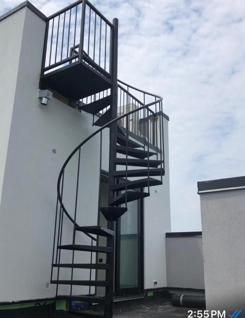 Black spiral staircase with rooftop platform on white building