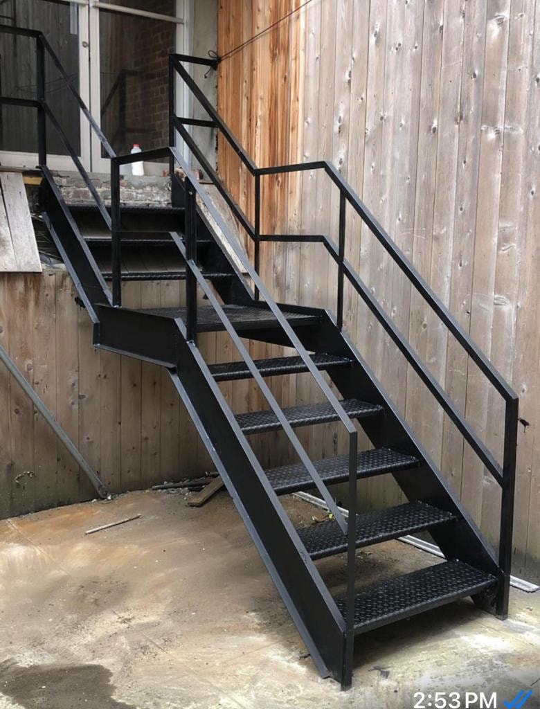 Black metal industrial staircase with wooden wall