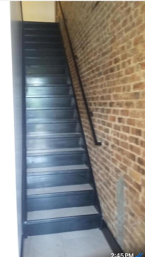 Narrow metal staircase between brick walls